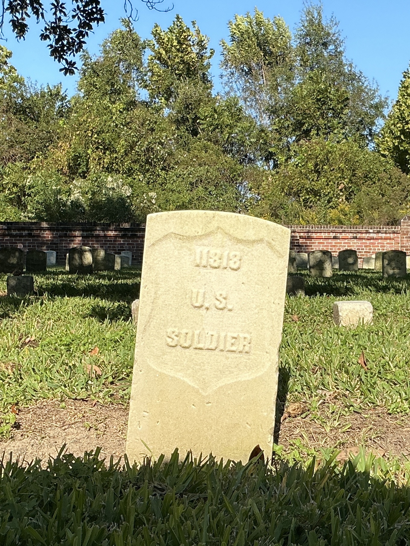 Front of historic upright marble headstone with recessed shield face.