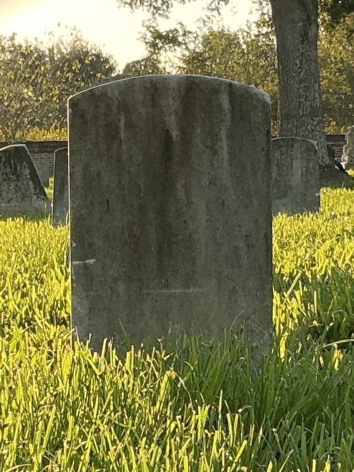Back of historic upright marble headstone with recessed shield face.