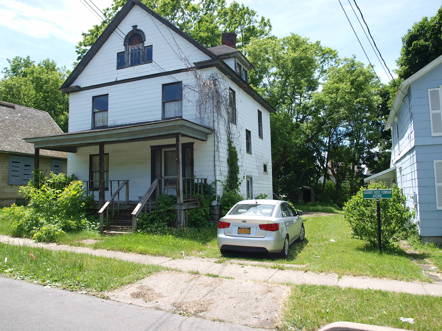 A three-story house with white siding, a porch, and a balcony to the right of the A.M.E. Church. 