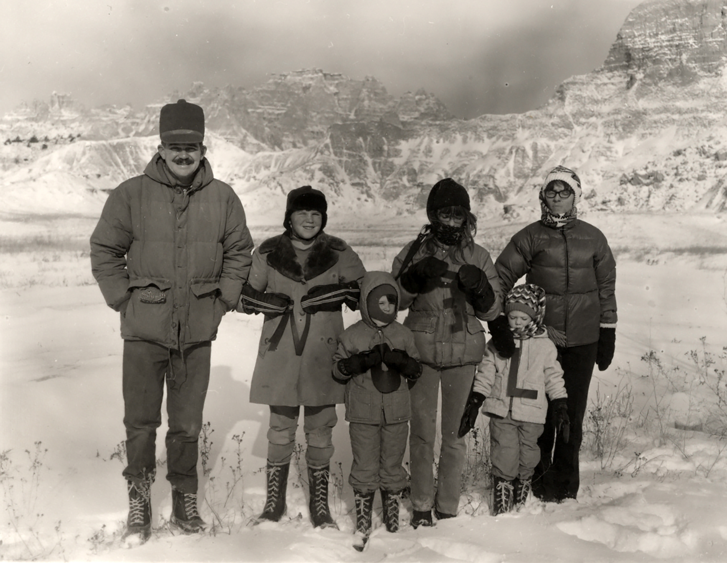 Swearingen family stands outside in the snow, in heavy coats and hats. 