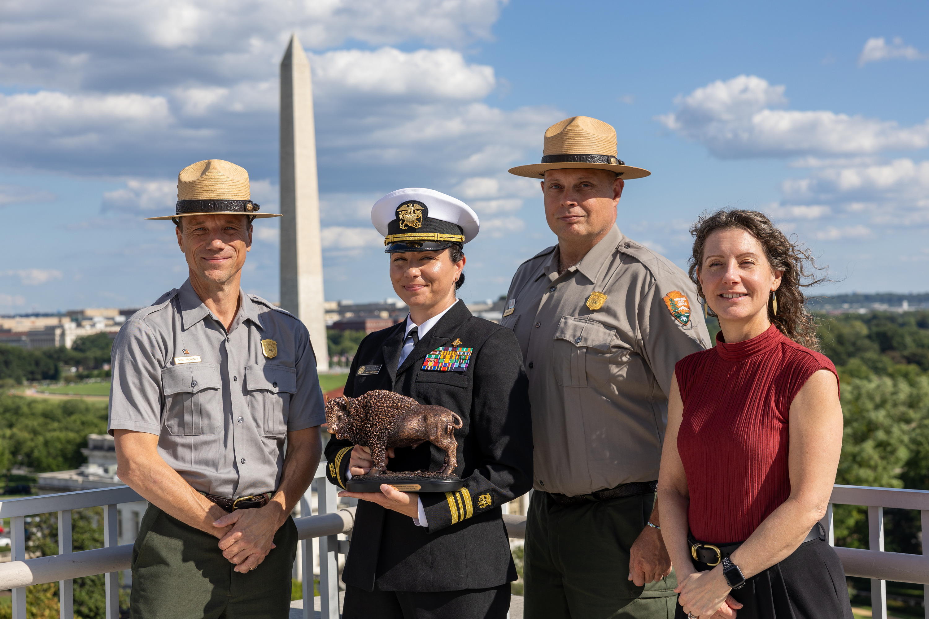 A female award recipient and three other people on a rooftop.