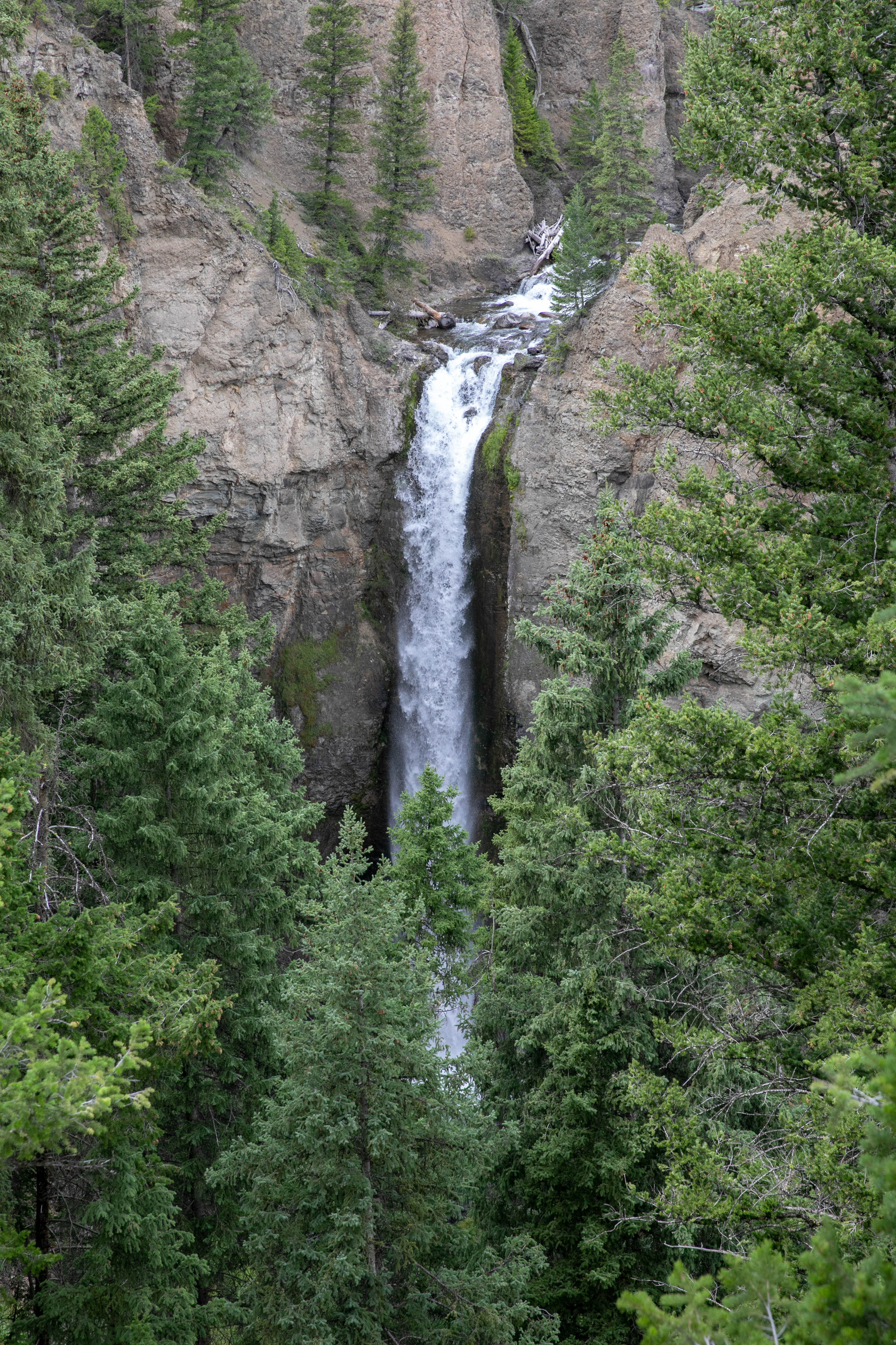 The waterfall flows over an eroded cliff and is narrow and tall.