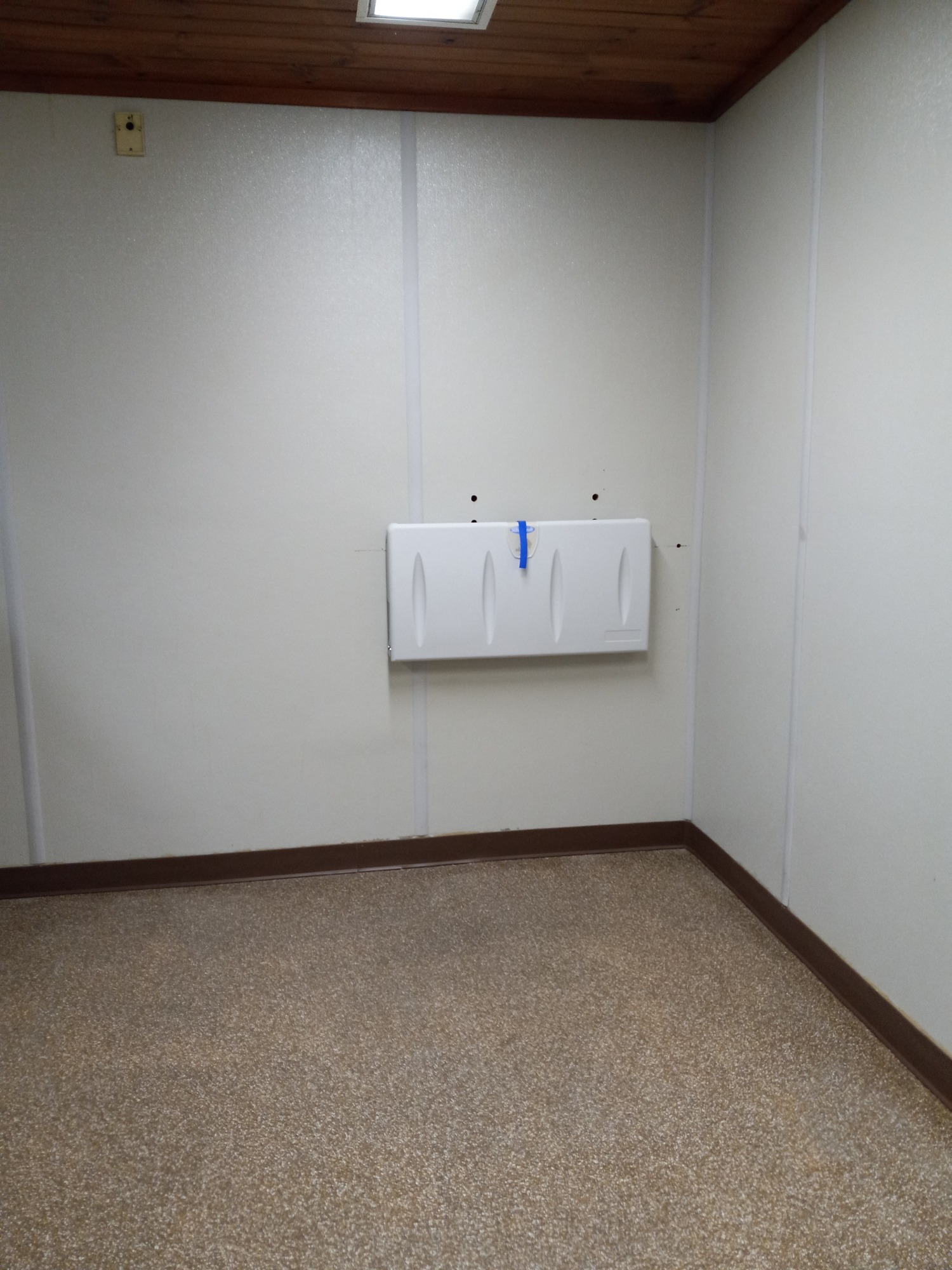 Interior of a restroom. A changing table is mounted to a wall near a corner of the room.