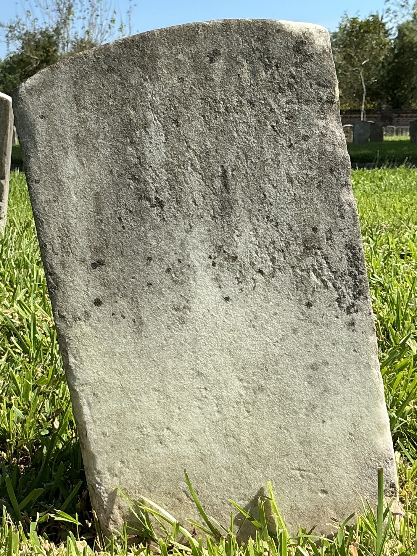 Back of historic upright marble headstone with recessed shield face.
