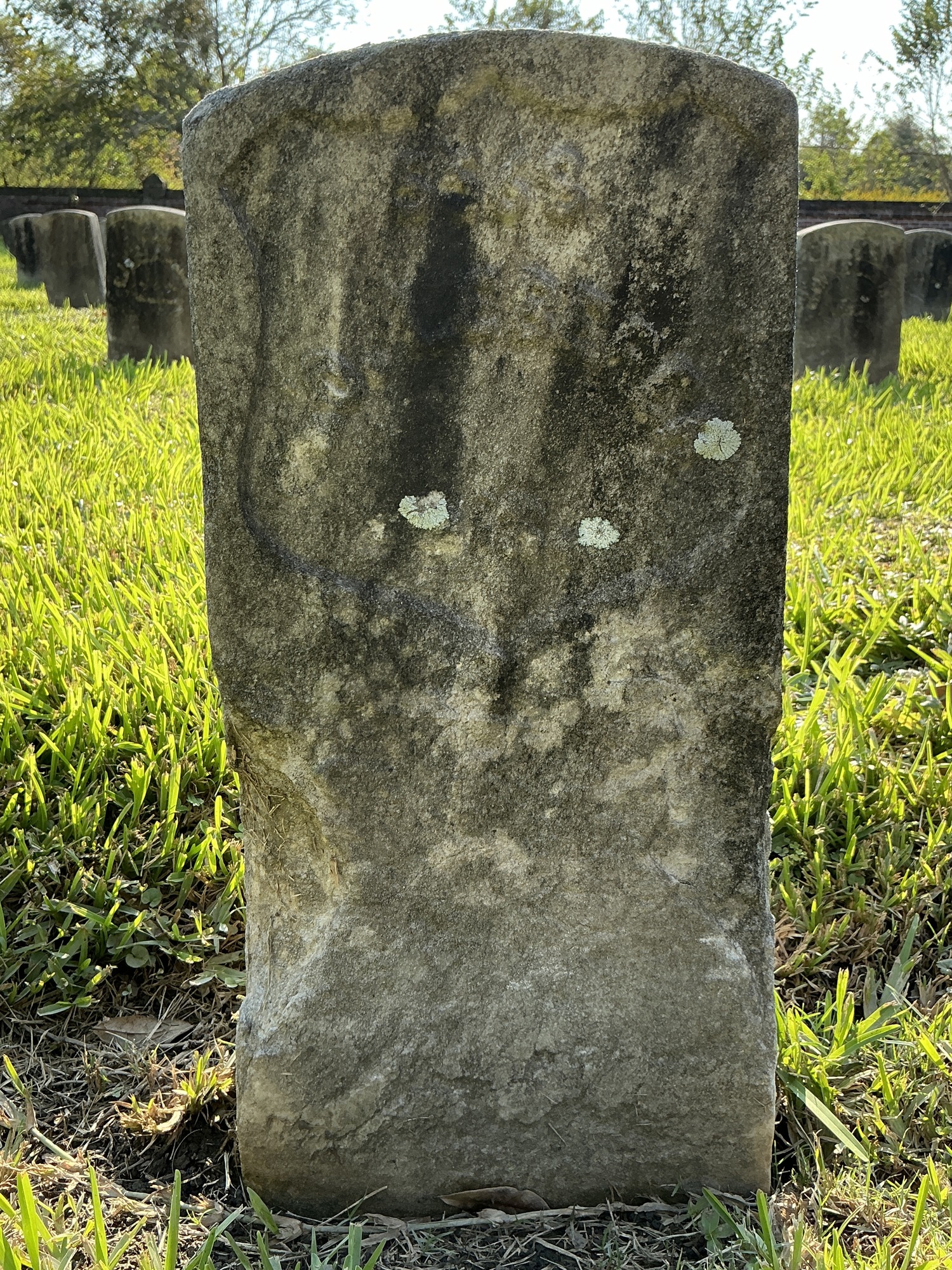 Front of historic upright marble headstone with recessed shield face.