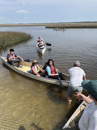 People in 3 canoes in marsh  
