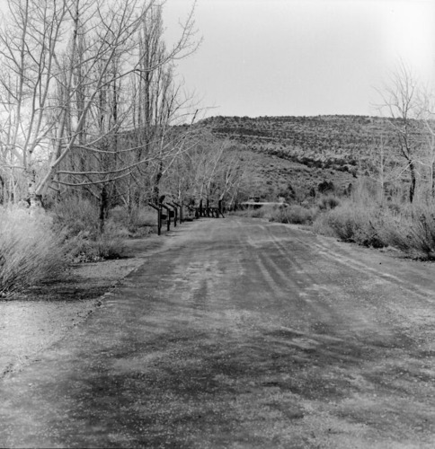 Wayside panel exhibit and plow next to the road and footbridge leading to residential area.