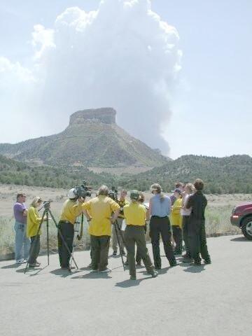 News media and park staff observe fire from a parking lot as a white smoke plume rises vertically over Long Mesa, Long Mesa Fire, Mesa Verde National Park, July-August 2002
