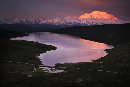 A landscape of hills, forests and a huge, snowy mountain