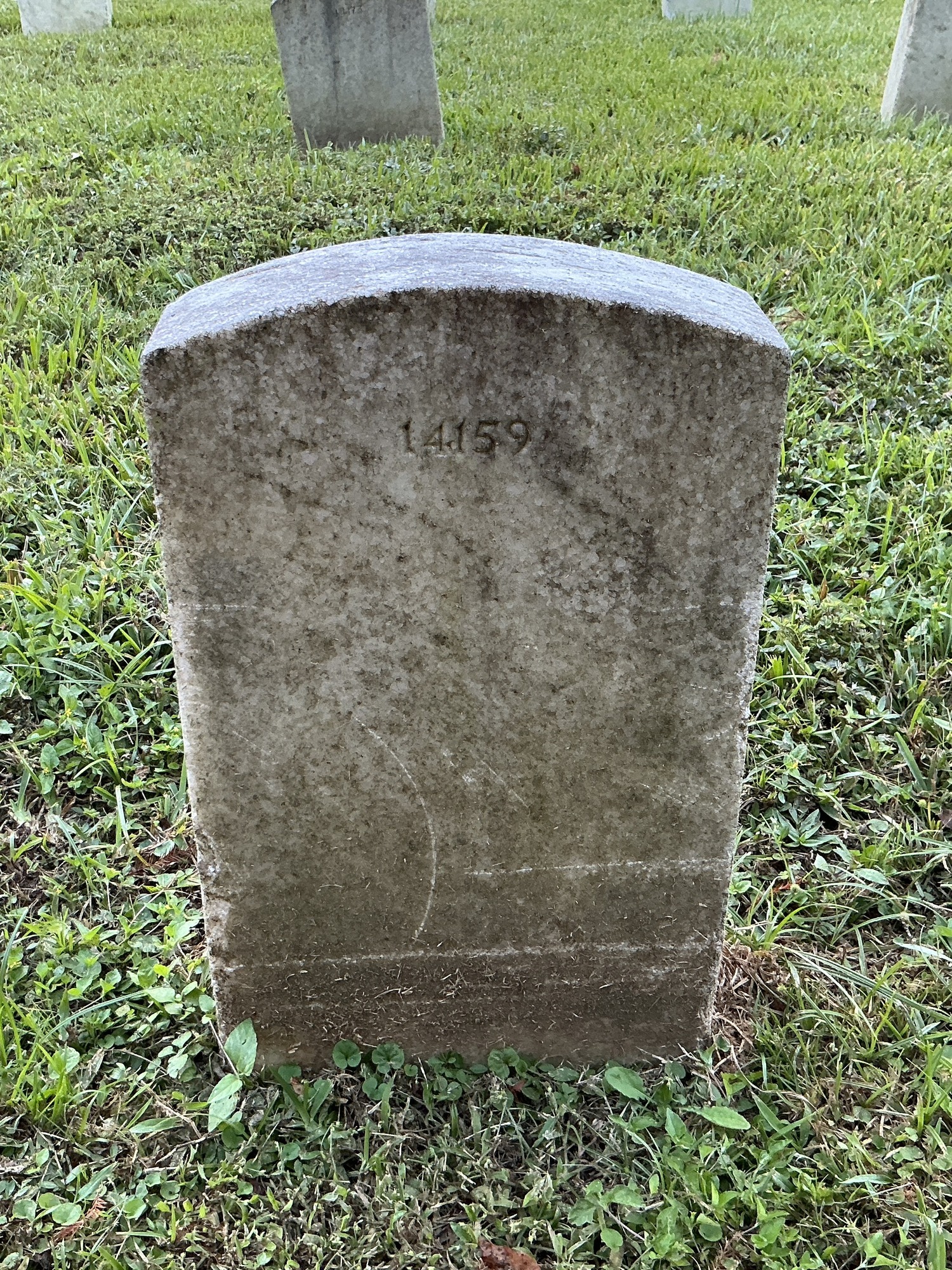 Back of historic upright marble headstone with recessed shield face.