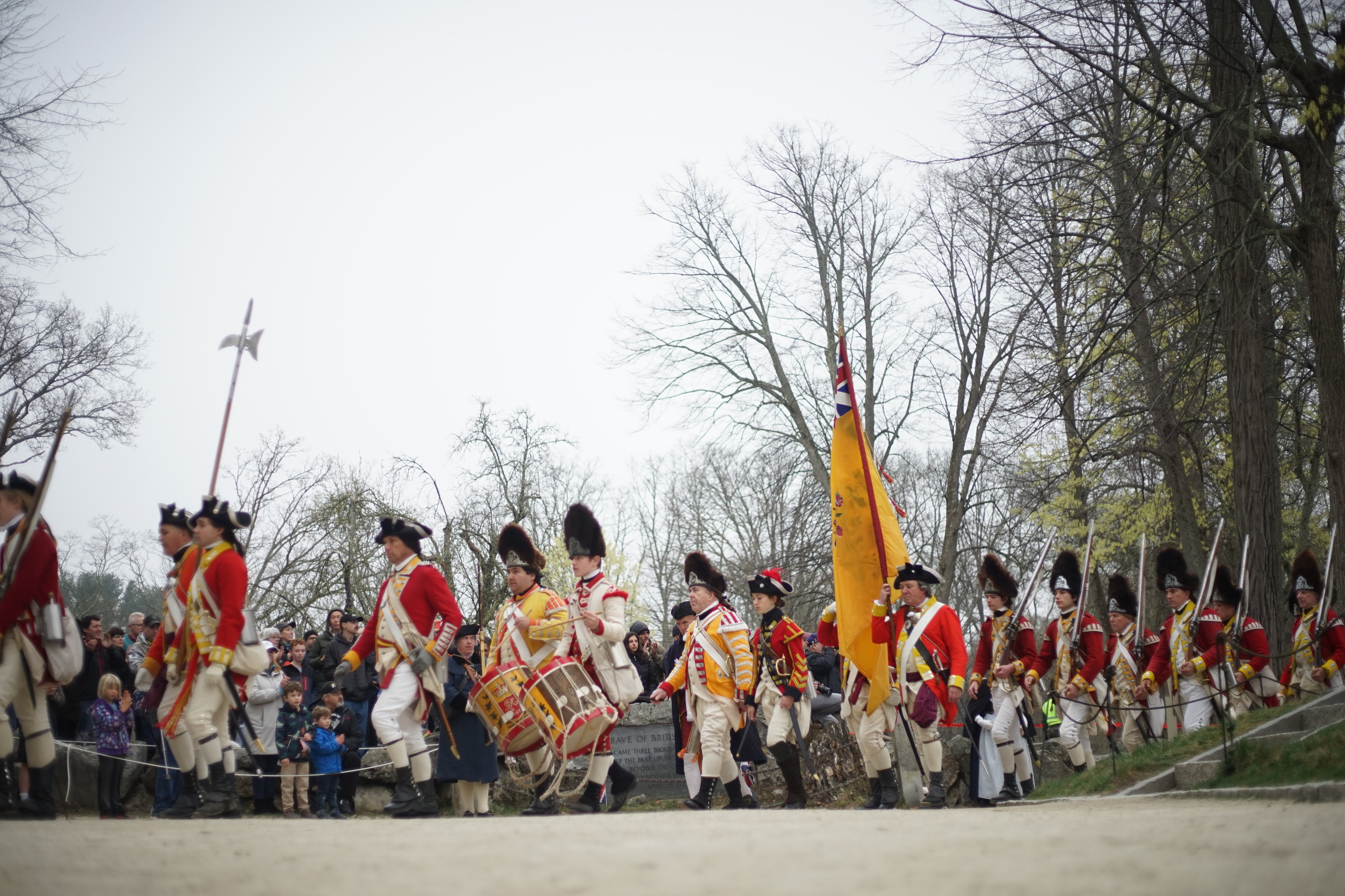 British troops marching from North Bridge past Grave of the British Soldiers, large crowd in background 