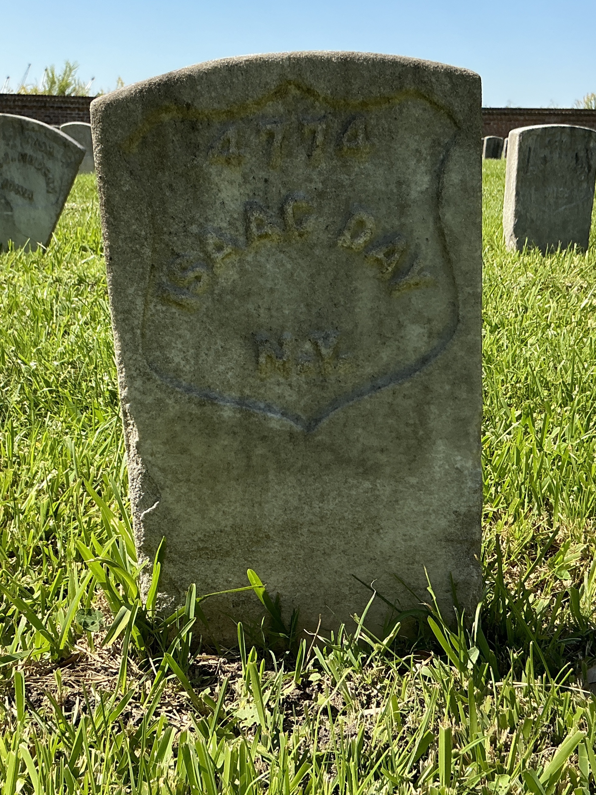 Front of historic upright marble headstone with recessed shield face.