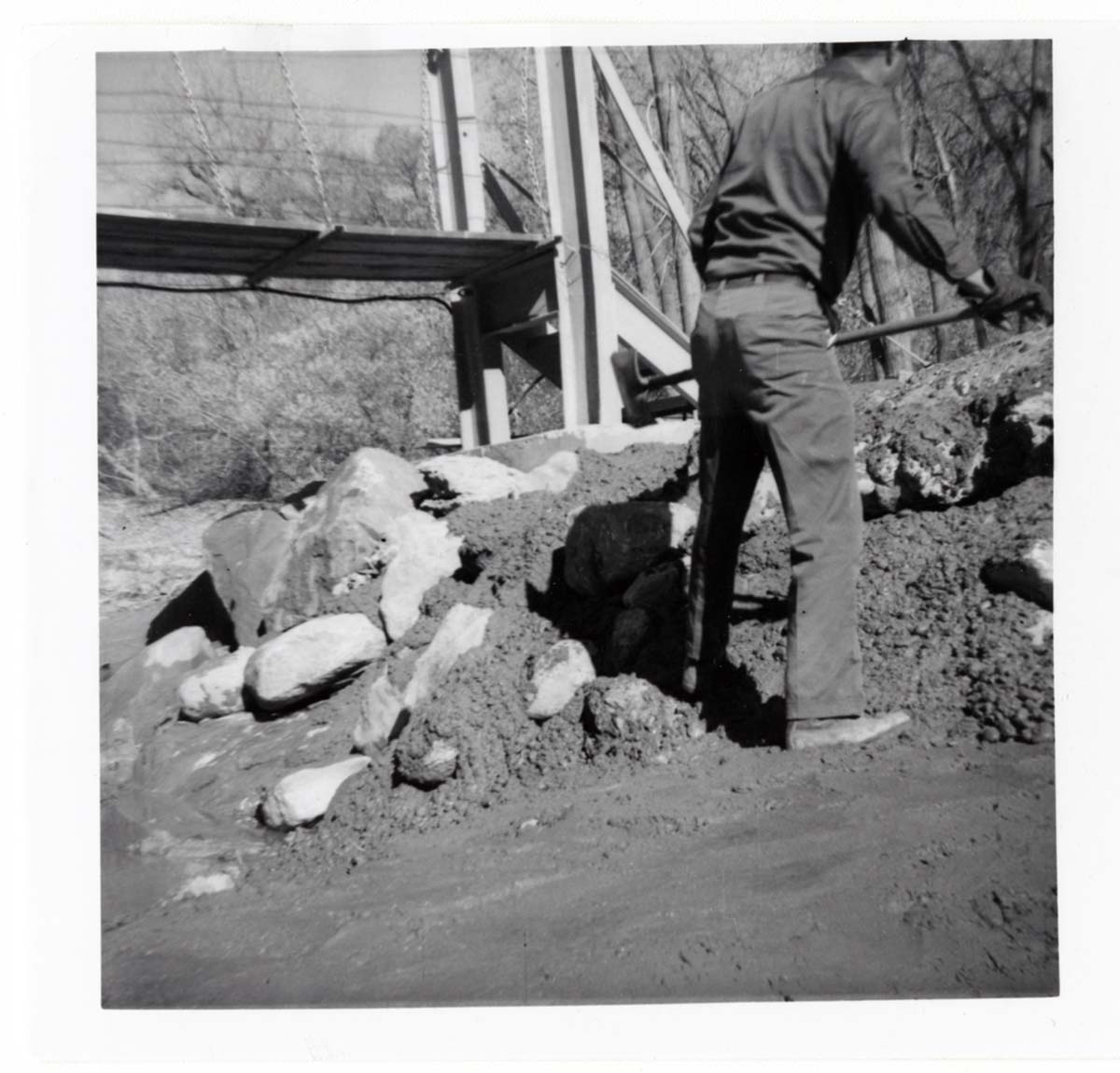 Man working on the protection/stabilization of the footings for the old Birch Creek suspension footbridge.