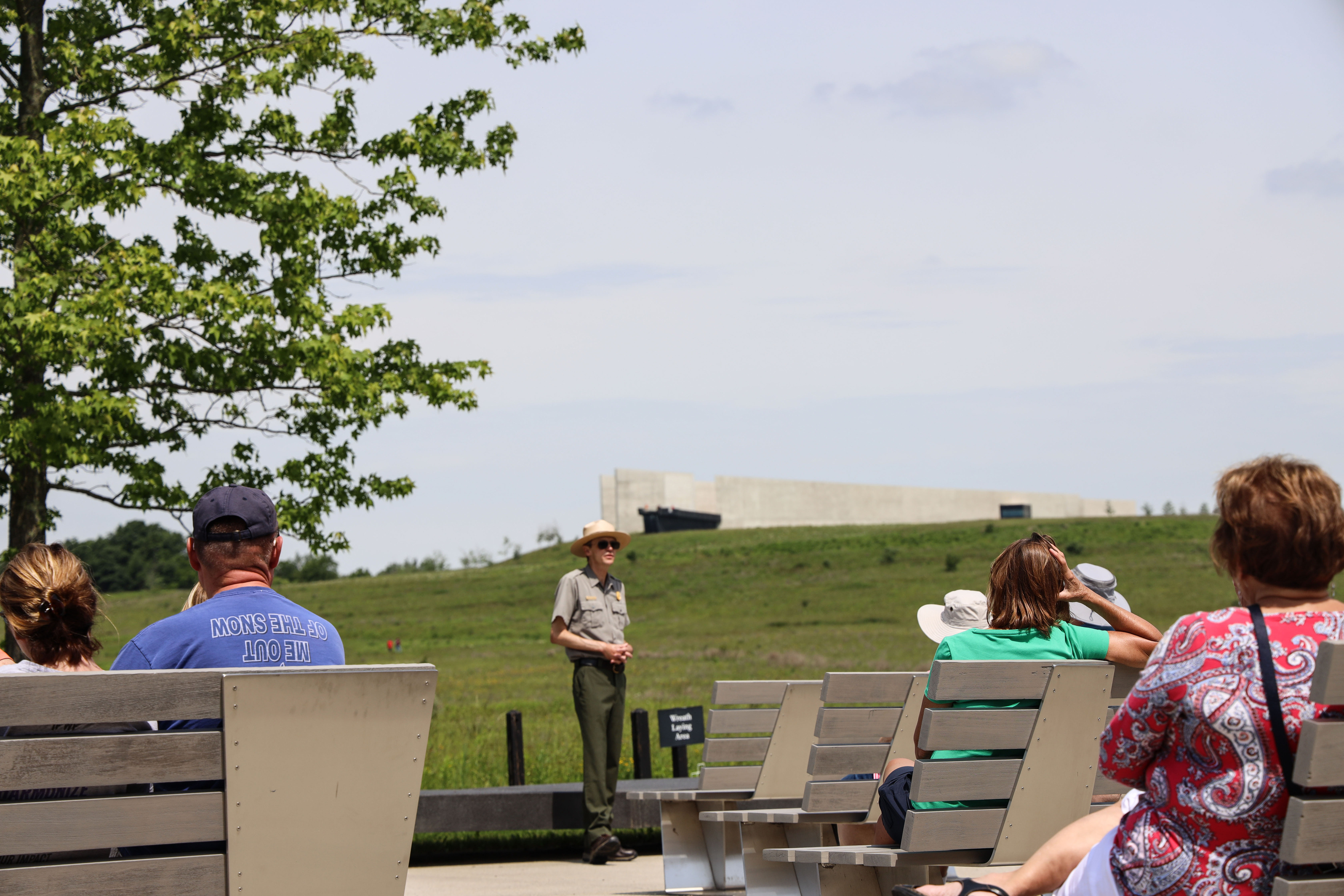 Flight 93 Park Ranger Walter Planitzer is seen giving a Flight 93 program to visitors at the flagpole located at the Memorial Plaza. The Visitor Center is shown from a distance.