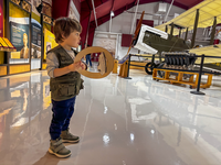 A child holds a junior ranger cutout head band, behind him is a plane display. 