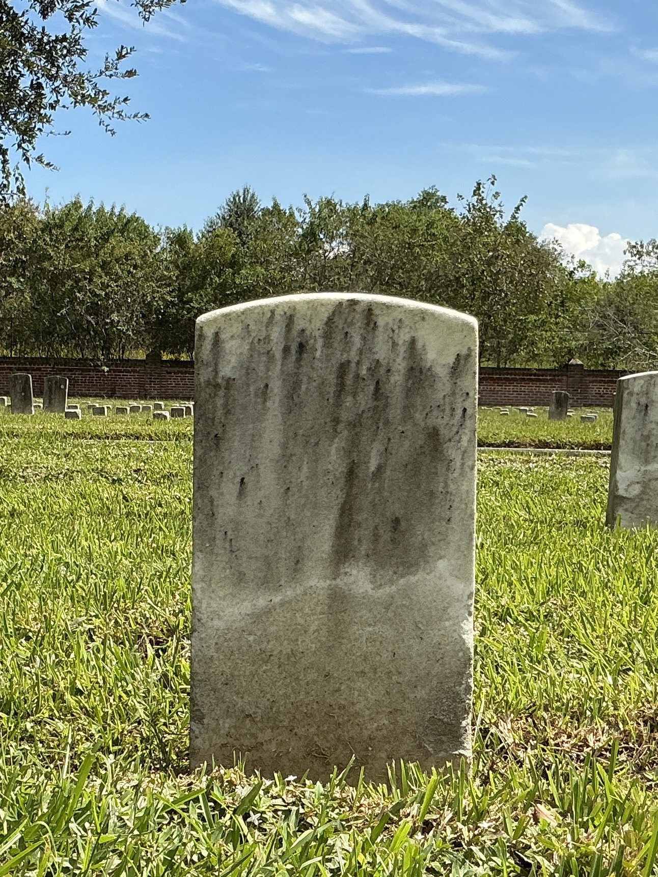 Back of historic upright marble headstone with recessed shield face.
