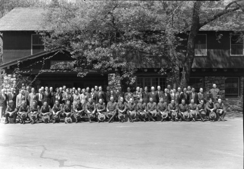 Group of permanent NPS personnel. FRONT ROW: L-R Ed Beatty, Assist. Naturalist; Frank Givens, Ranger; Duane Jacobs, Ranger; Harry During, Ranger; Lon Garrison, Ranger; John Bingaman, Ranger; Jerry Mernin, Ranger; John Wosky, Asst. Supt.; L.C. Merriam, Supt.; F.S. Townsley, Chief Ranger; John Wegner, Asst. Chief; Gus Eastman, Ranger; Carl Danner, Ranger; Vernon Lowery, Ranger; Cliff Anderson, Ranger; Homer Hoyt, Ranger; Otto Brown, Ranger; Stan Joseph, Asst. to Supt.; Jim Stakel, Ranger; Art Holmes, Ranger; Ralph H. Anderson, info. clerk & photographer; STANDING: Frank Ewing, Employment Mgr.; Russell Sprinkel, Chief Clerk; E.M. Hilton, Park Engineer; Dwight Humphries, Clerk Steno.; Jim Harrison, Sec. to Supt.; Dan Cookson, electrician; Lee Rust, road maint.; Art Guinn, Accounting, personnel (?); Harvey Ashworth, electrician; Hazel Adams, steno; Art Moen, warehouse; Henry Listina, equip. whse.; Eliz. Godgrey, sec. Museum; R. Hodges; Walt Gann, electrician; Essie Kimball, file clerk; Joe Jenkins, chief electrici