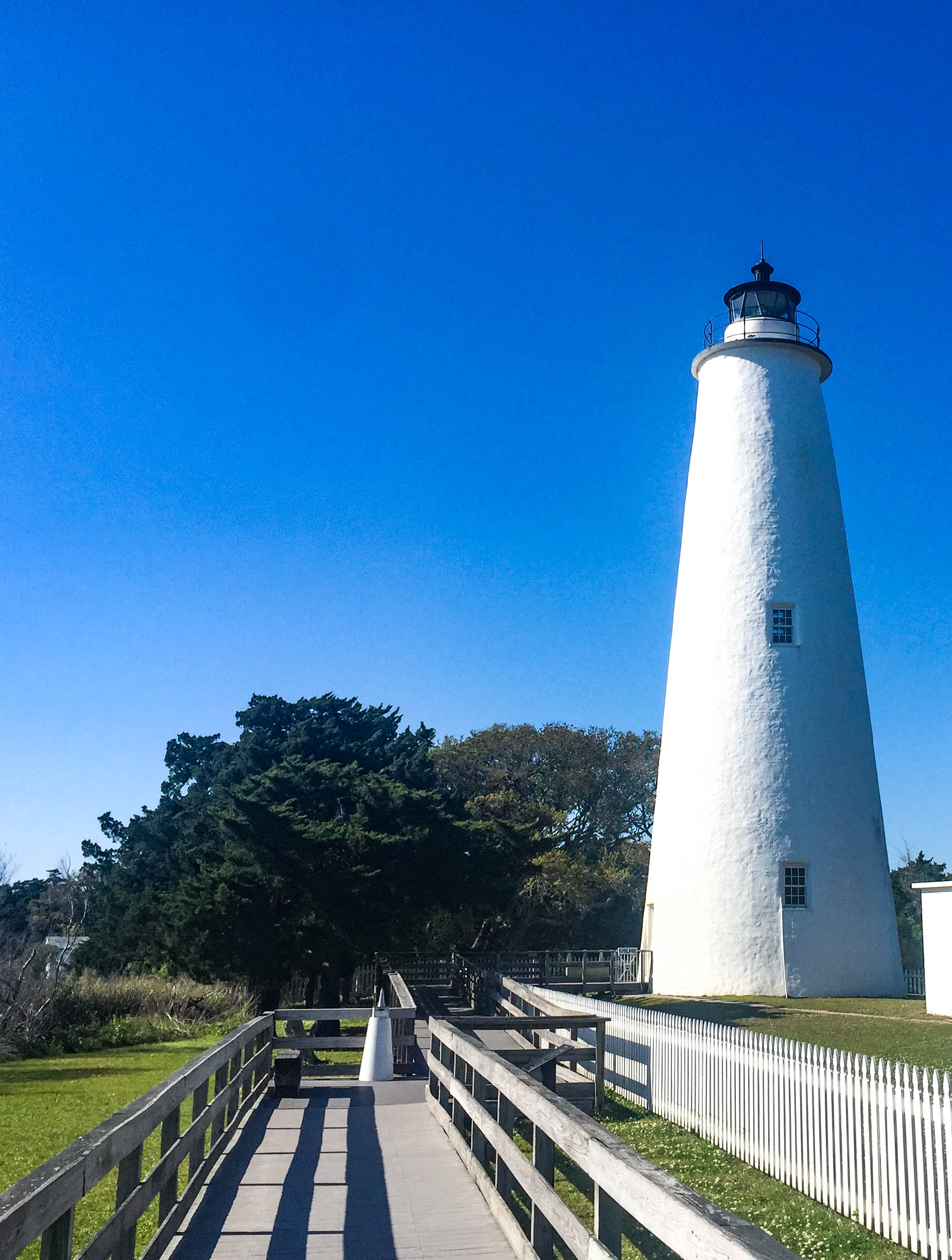 White lighthouse at the end of a boardwalk