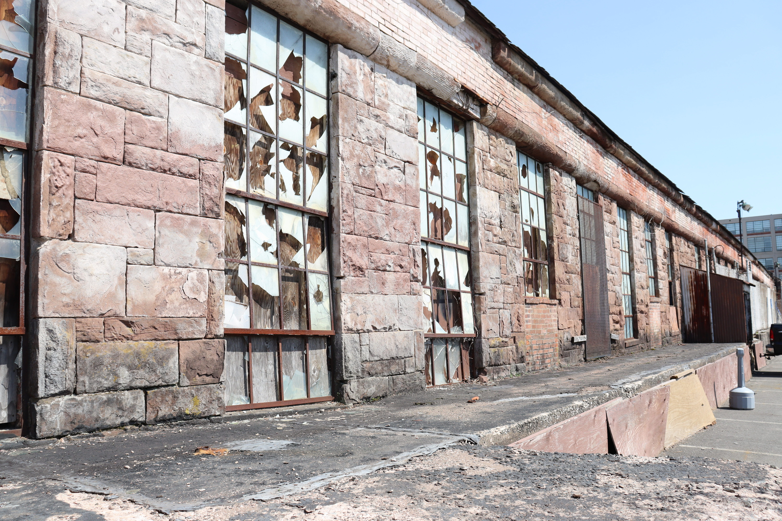 One story brownstone building with all of the windows broken and boarded up from inside.