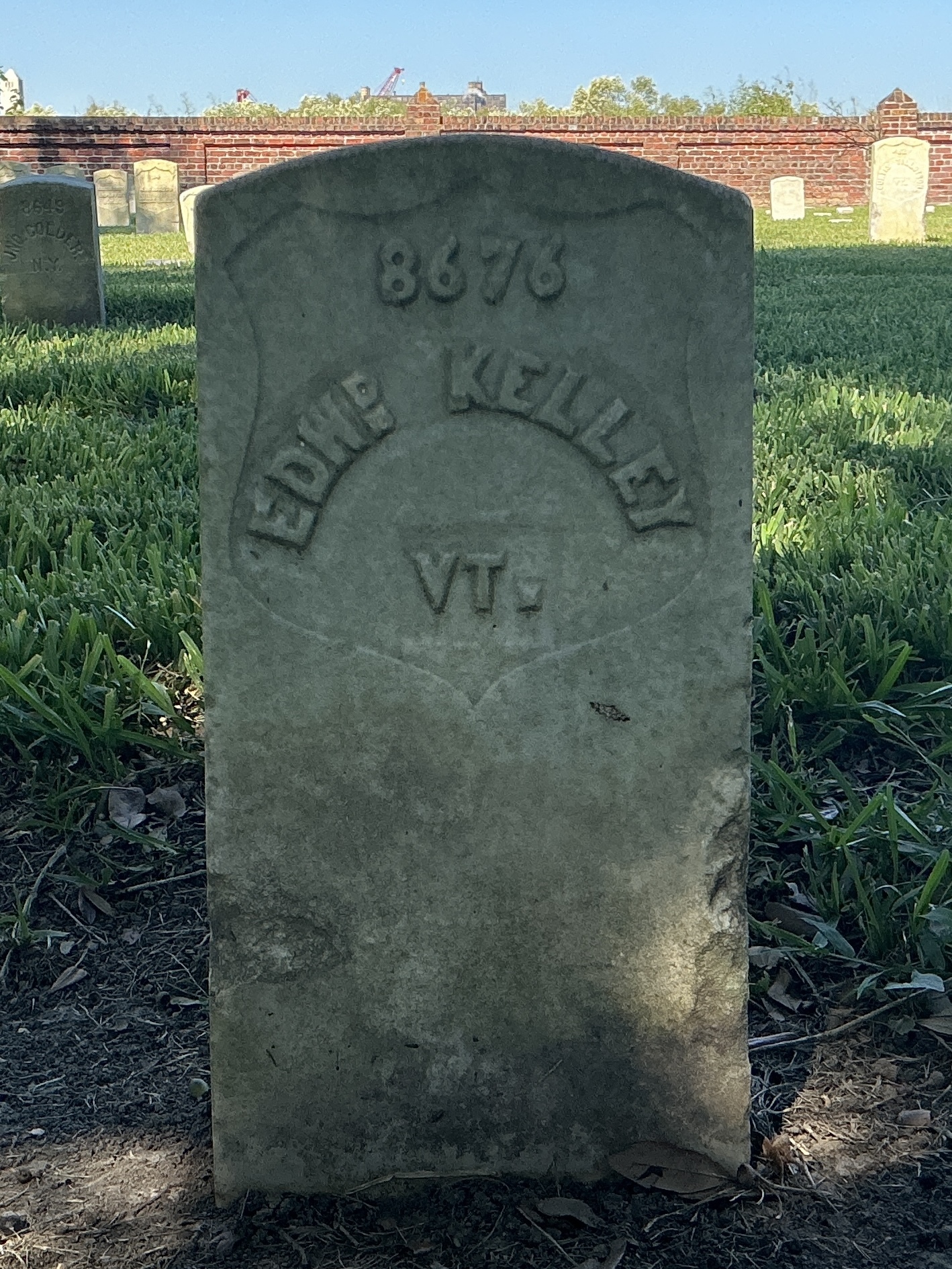 Front of historic upright marble headstone with recessed shield with recessed lettering face.