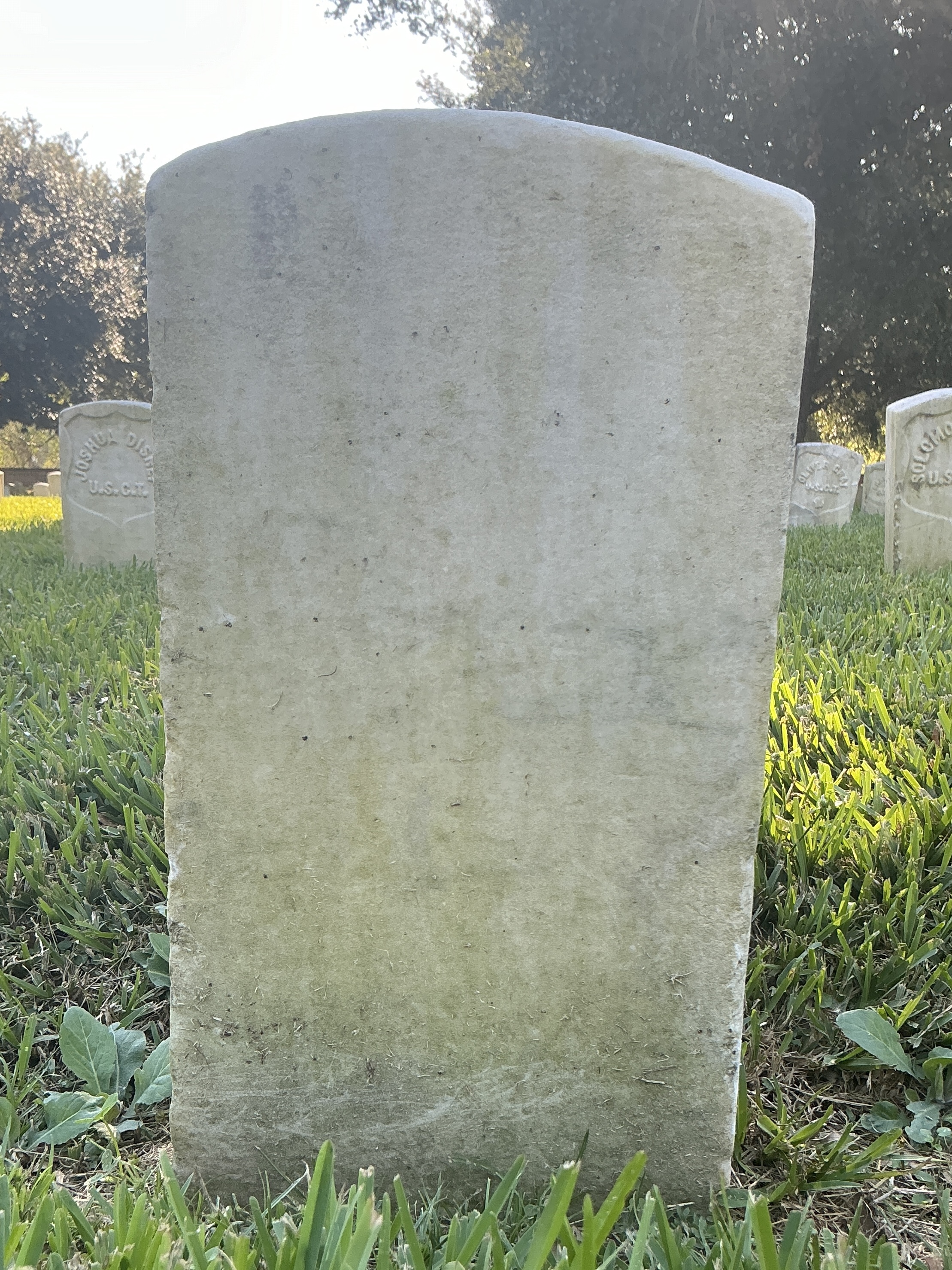 Back of historic upright marble headstone with recessed shield face.
