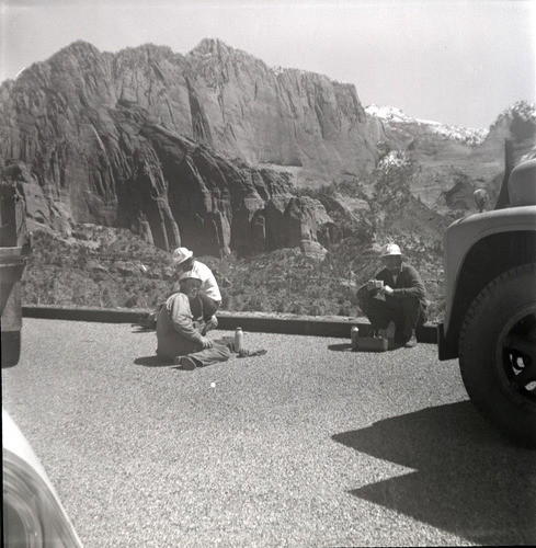 Workers rest for lunch during rebuilding of rock retaining wall alongside road at the tunnel.