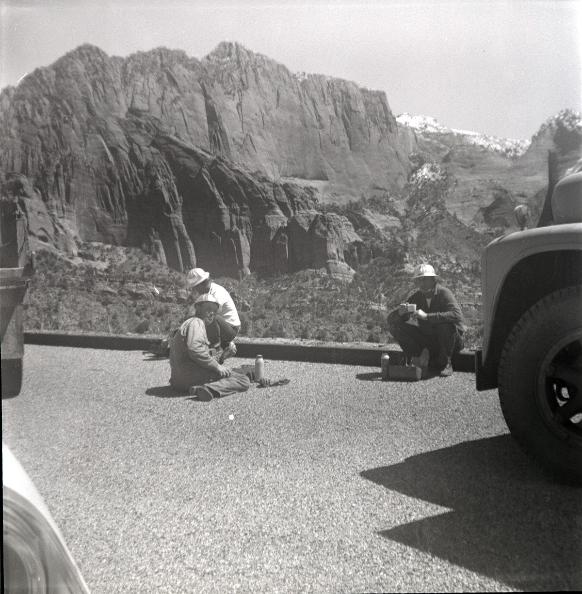 Workers rest for lunch during rebuilding of rock retaining wall alongside road at the tunnel.