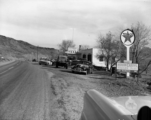 Roadside signs near Zion. 'A collection of cars, trucks and tractors in the parking area in front of the 101 Ranch service station. Limited space between station and Highway 15 [State Route 15, now State Route 9].'