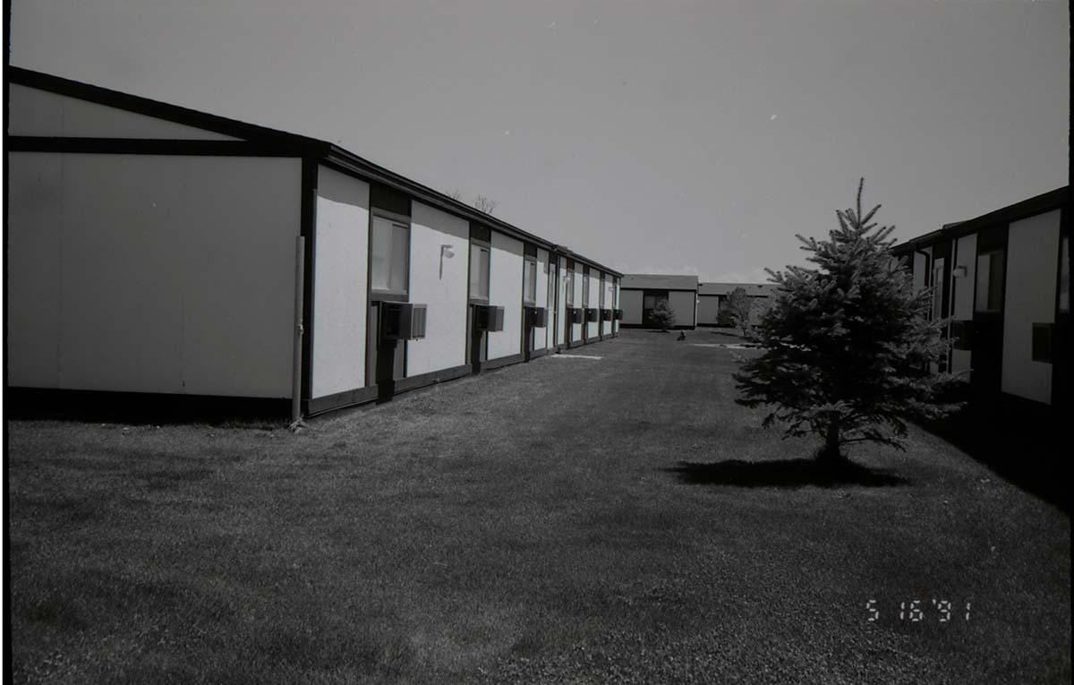 Backside of barracks with landscaping between buildings. [Image possibly for comparative housing study]
