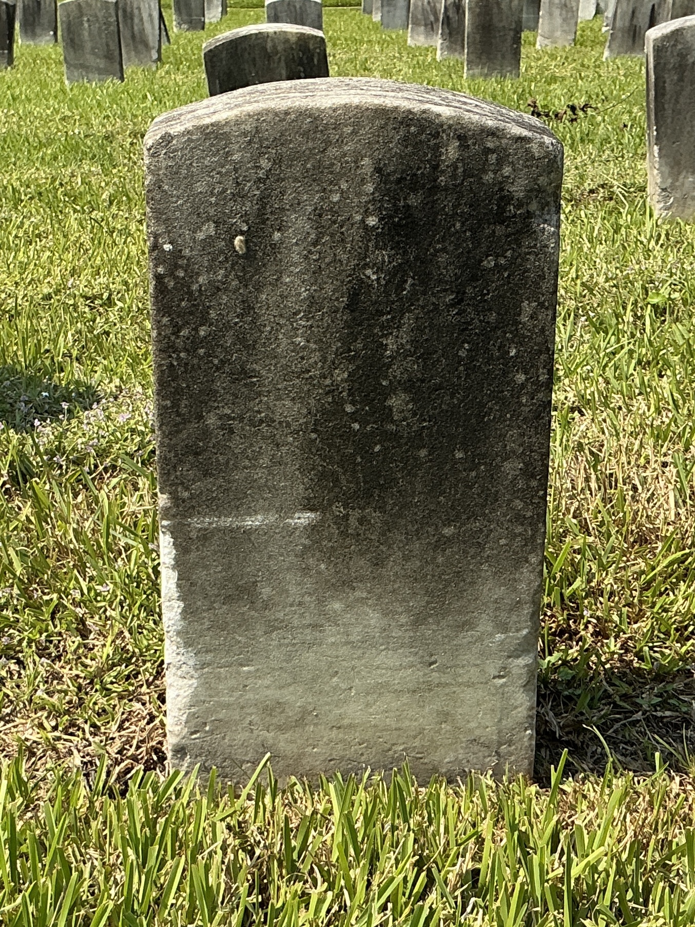 Back of historic upright marble headstone with recessed shield face.
