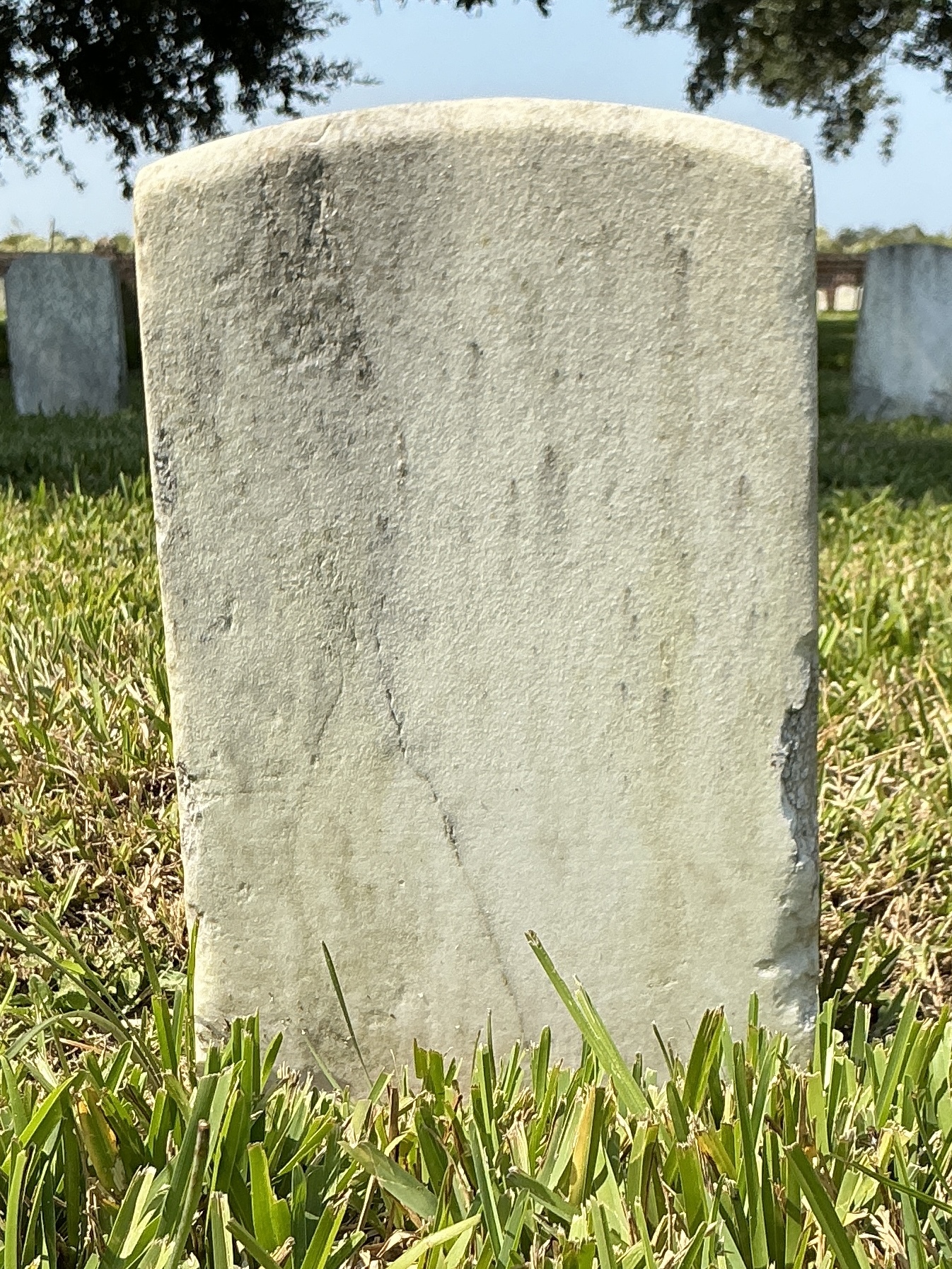 Back of historic upright marble headstone with recessed shield face.