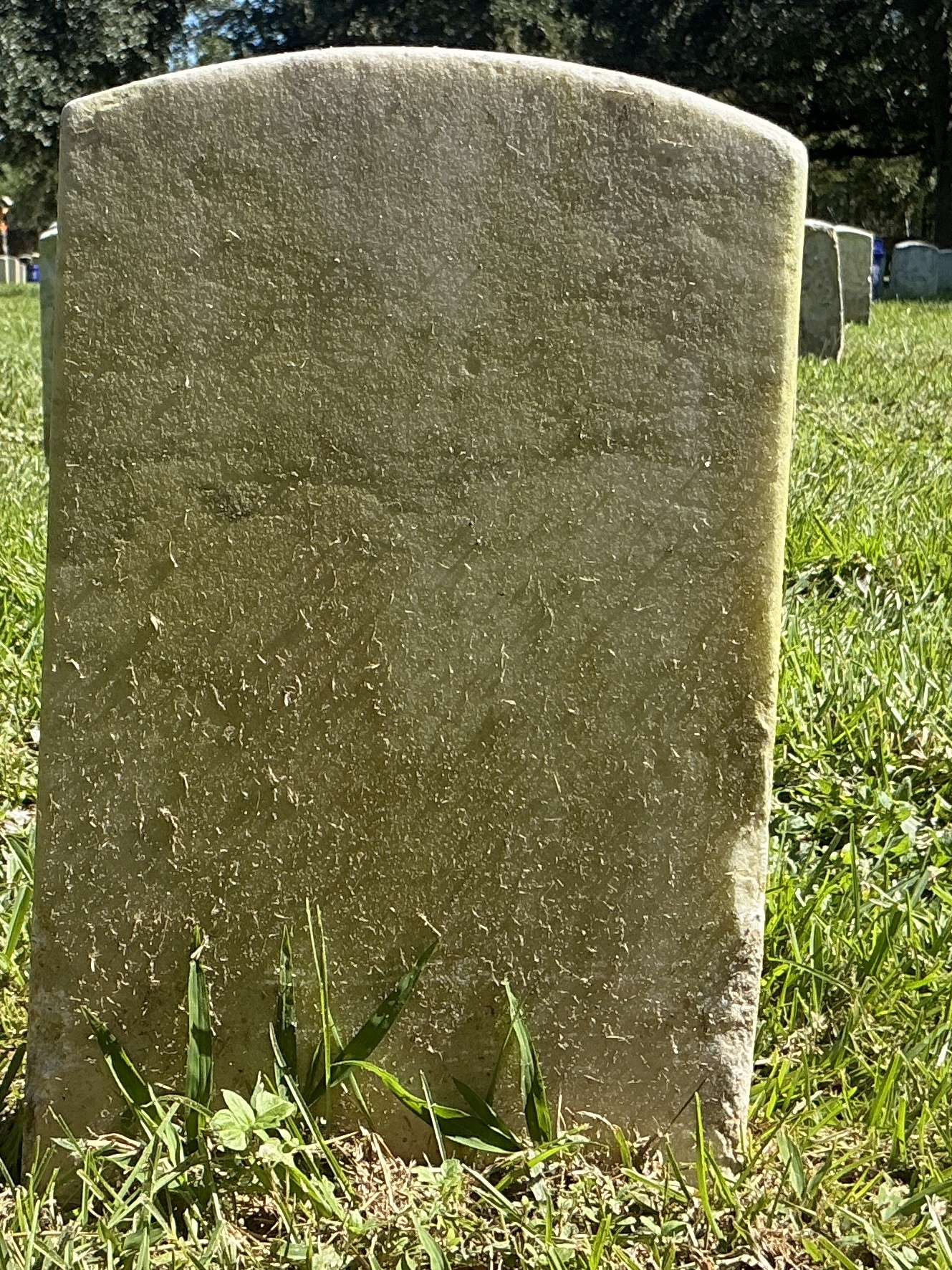 Back of historic upright marble headstone with recessed shield face.