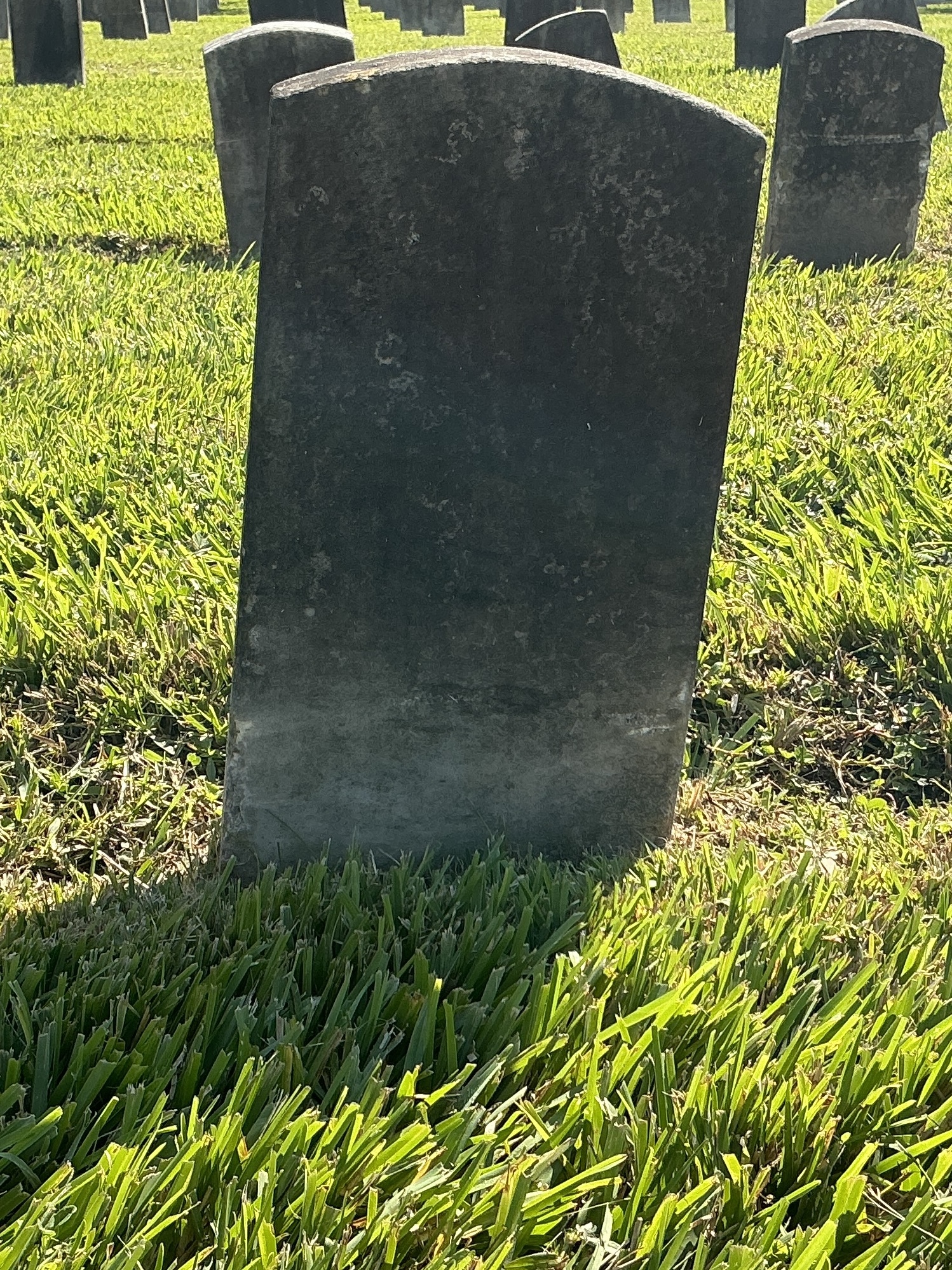 Back of historic upright marble headstone with recessed shield face.