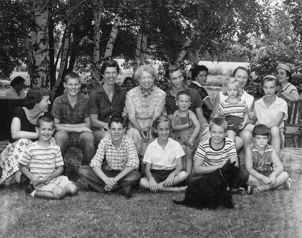 A large group of adults and children gathered on a lawn.