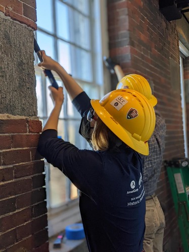 Two people removing historic windows from Building 22.