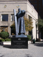 A statue of a man holding a book in front of a building.