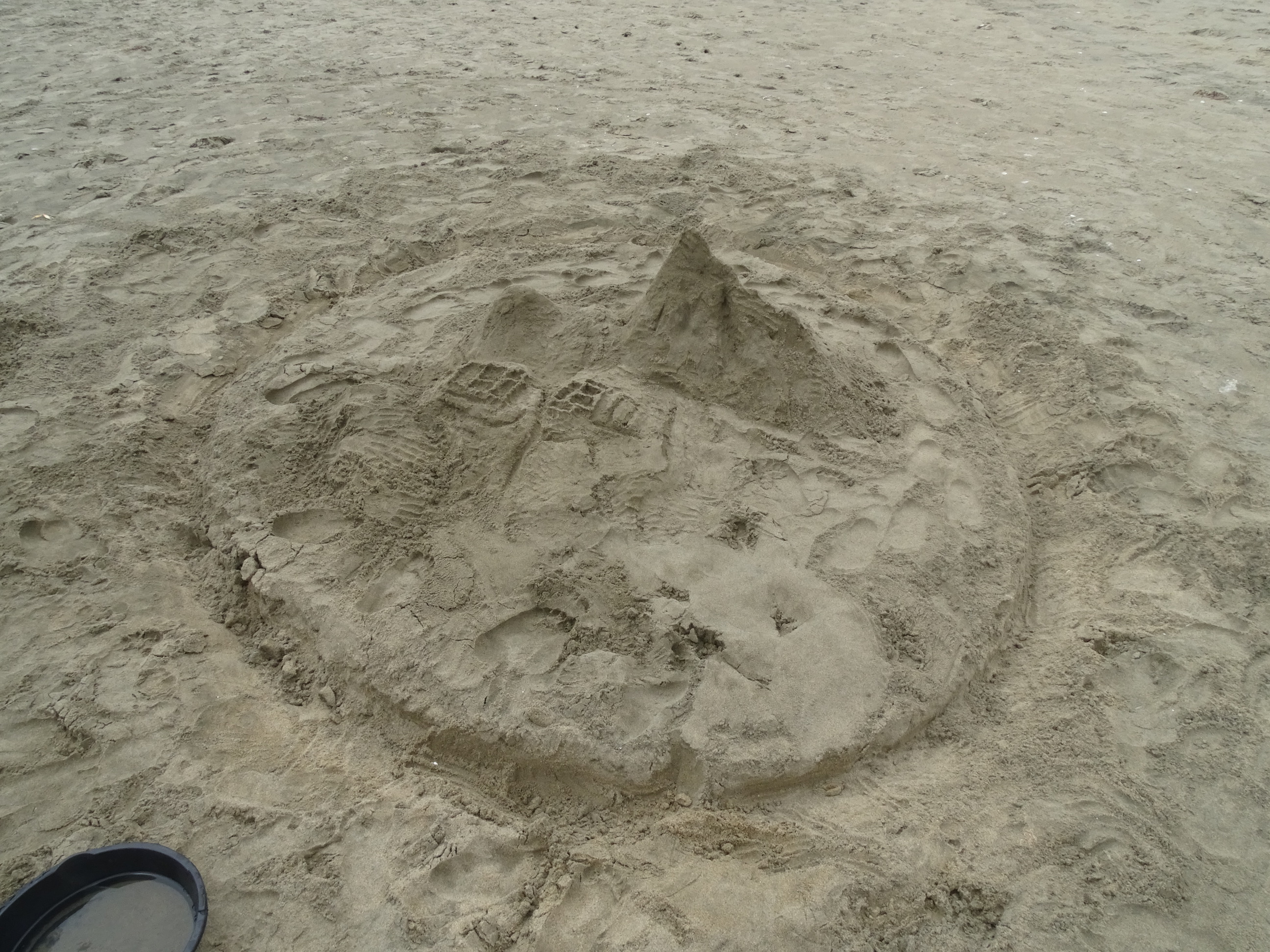A sand sculpture of a steep-sided mountain rising above Incan ruins.