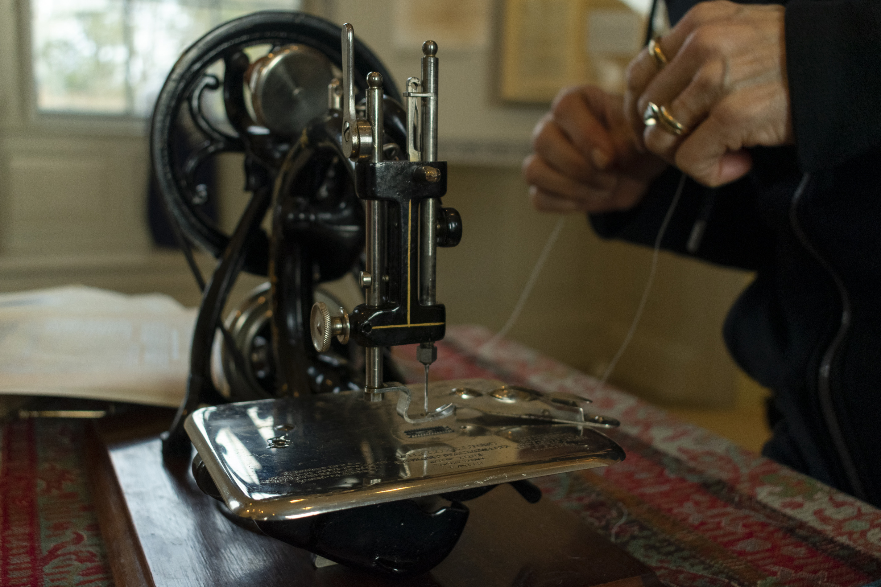 Close up of hands threading a sewing machine.