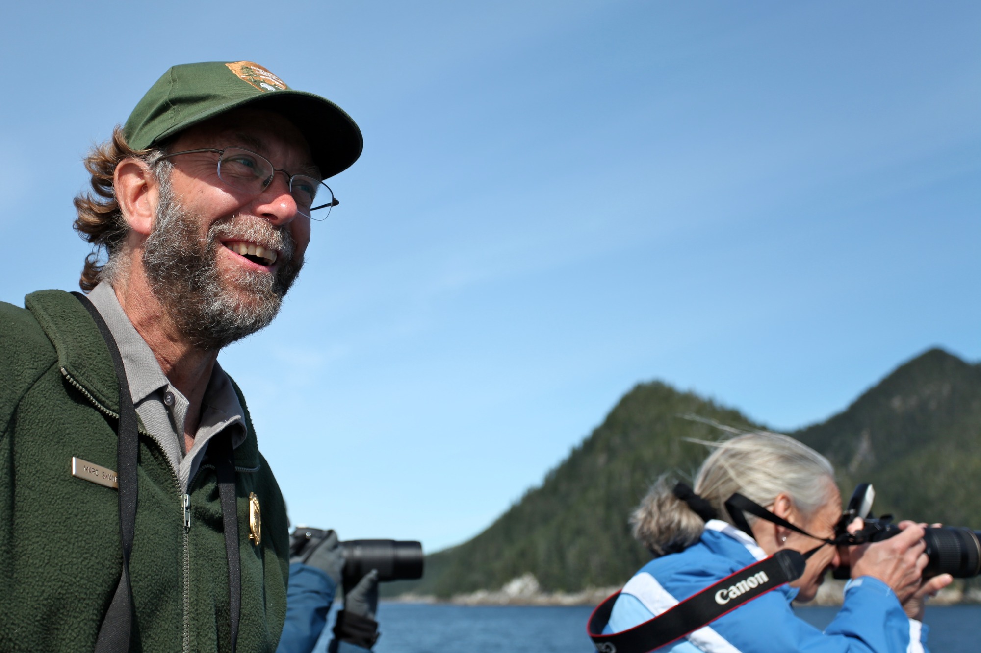 Interpretive Ranger Marc Swanson with visitors taking photographs while aboard the M/V Glacier Express.