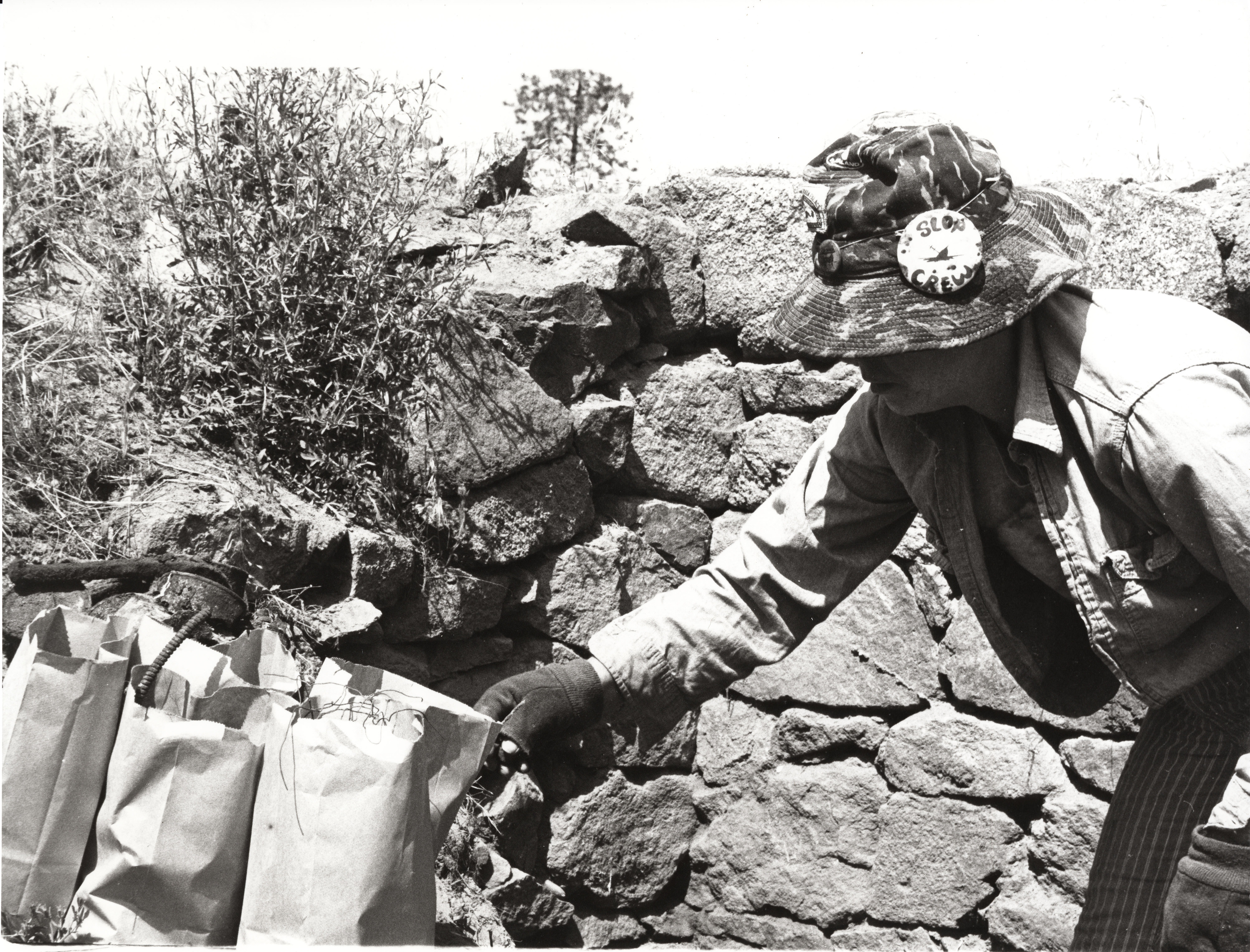 Black and white photograph of a person reaching for some bags