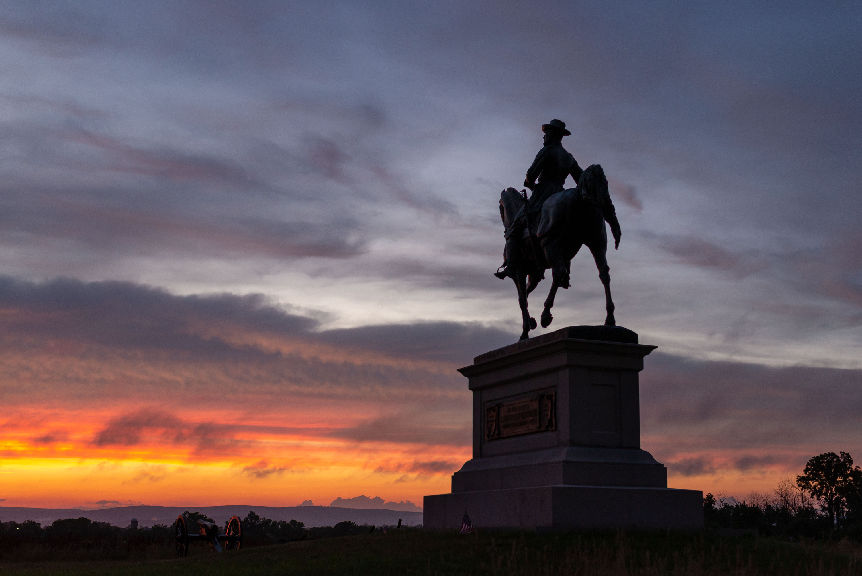 An equestrian statue silhouetted by a sunset.