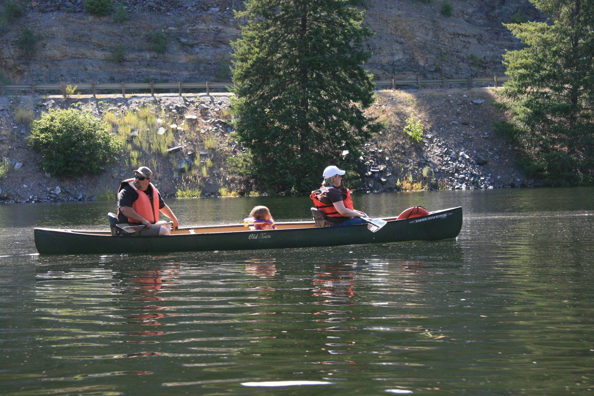 Color photograph of two adults and a child in a canoe on a river