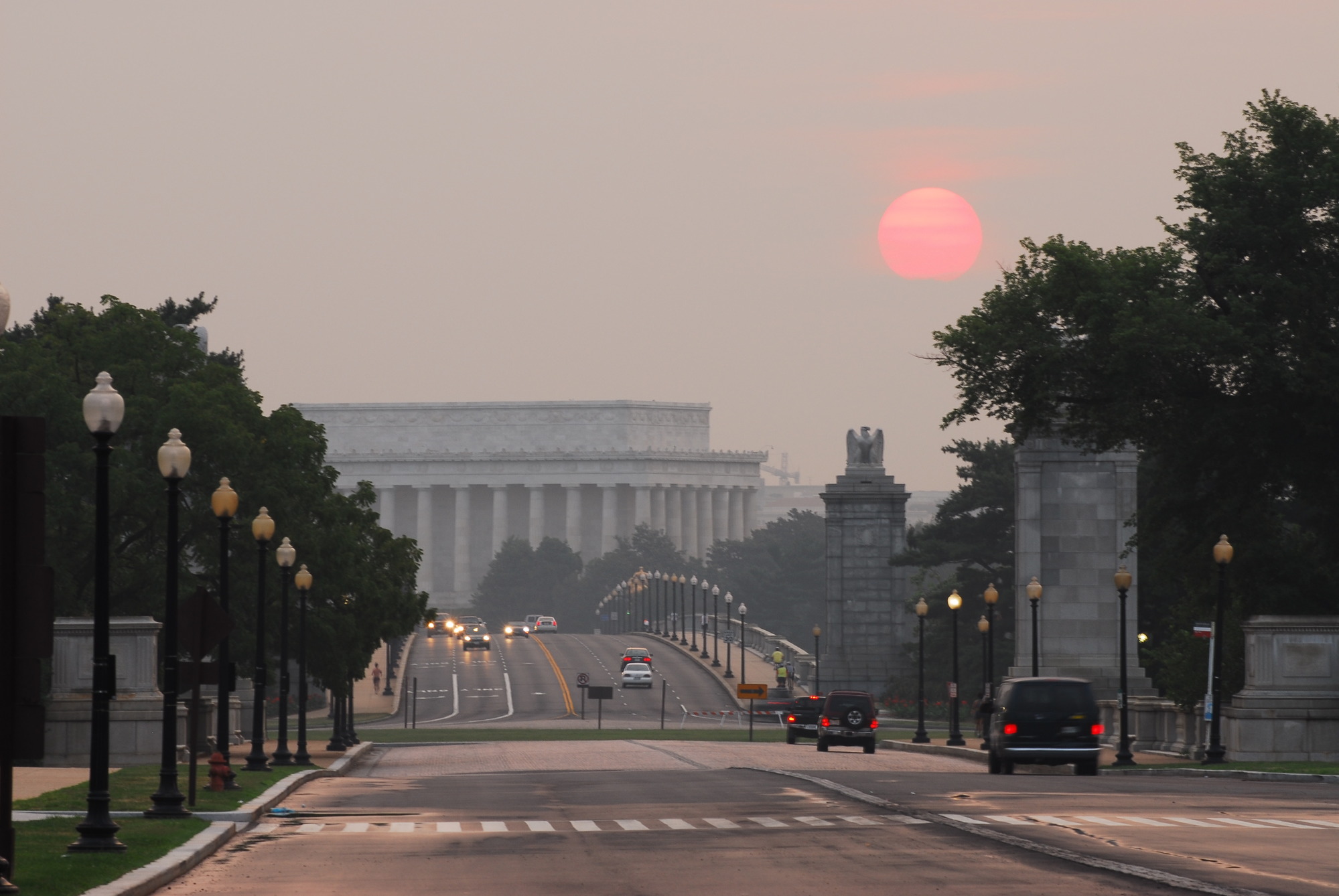 A red sun rises over Arlington Memorial Bridge, which leads to the Lincoln Memorial. 
