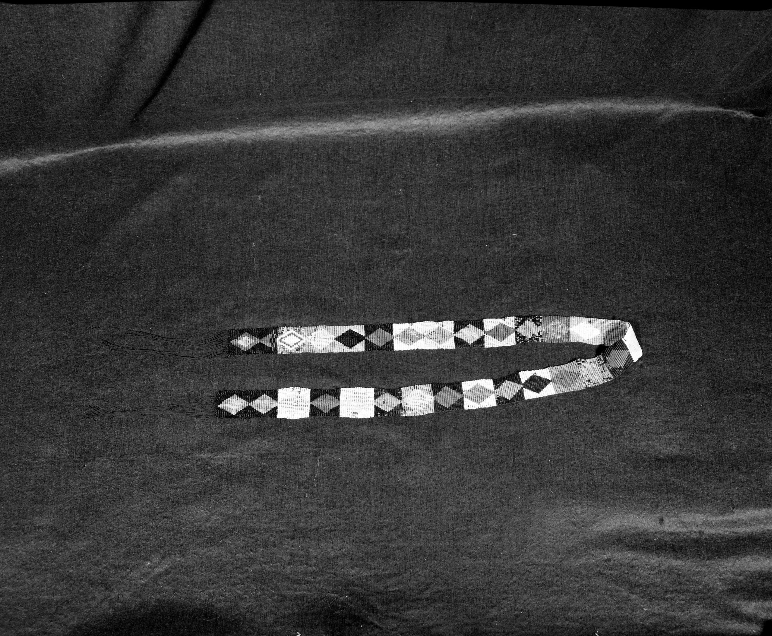 Marie Rozier Collection, Catalog No. 136. Object: Miwok beaded belt. Dimensions: 39 x 1 1/4". Materials: Black cotton thread; red, black, orange, greasy yellow, turquoise, medium blue, white, medium green, plain blue with scattered mismatched beads in pink, clear green and other colors. Technology: Loomless beadwork technique, double weft. Collection History: Made by Mrs. Louise Fuentes in 1950s. Purchased by Miss Rozier. Photographed by Michael Dixon in December 1982. Catalogued by Craig Bates and Barbara Beroza. Yosemite Collections, National Park Service.