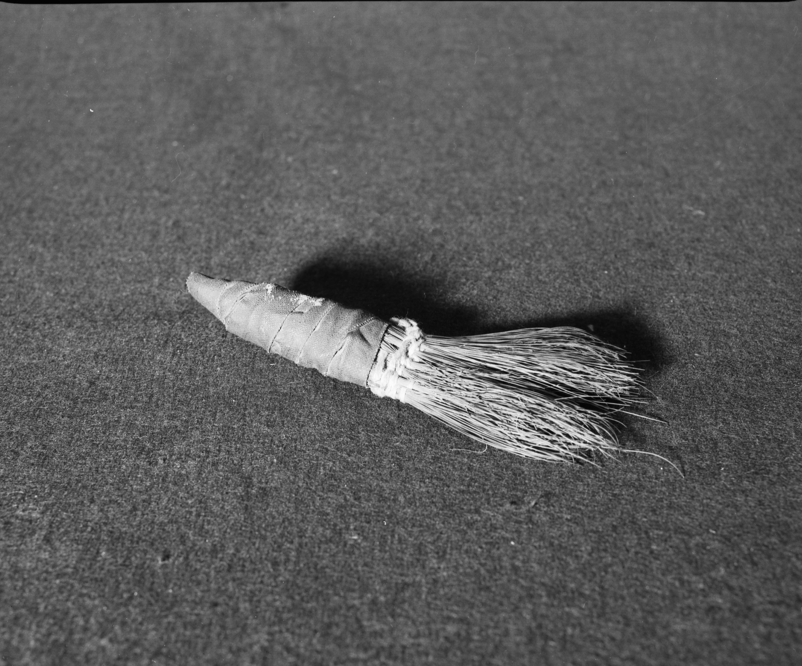 Marie Rozier Collection, Catalog No. 28. Object: Miwok brush. Dimensions: 6 1/2". Materials: soaproot fiber, cotton thread, cotton string, black woven electrician's tape. Collection History: Over 100 years old in 1950s. Used by grandmother of Maggie Antonini. Made in Mariposa county. Called "shoo-poo" there. Given by Mrs. Antonini. Photographed by Michael Dixon in December 1982. Catalogued by Craig Bates and Barbara Beroza. Yosemite Collections, National Park Service.