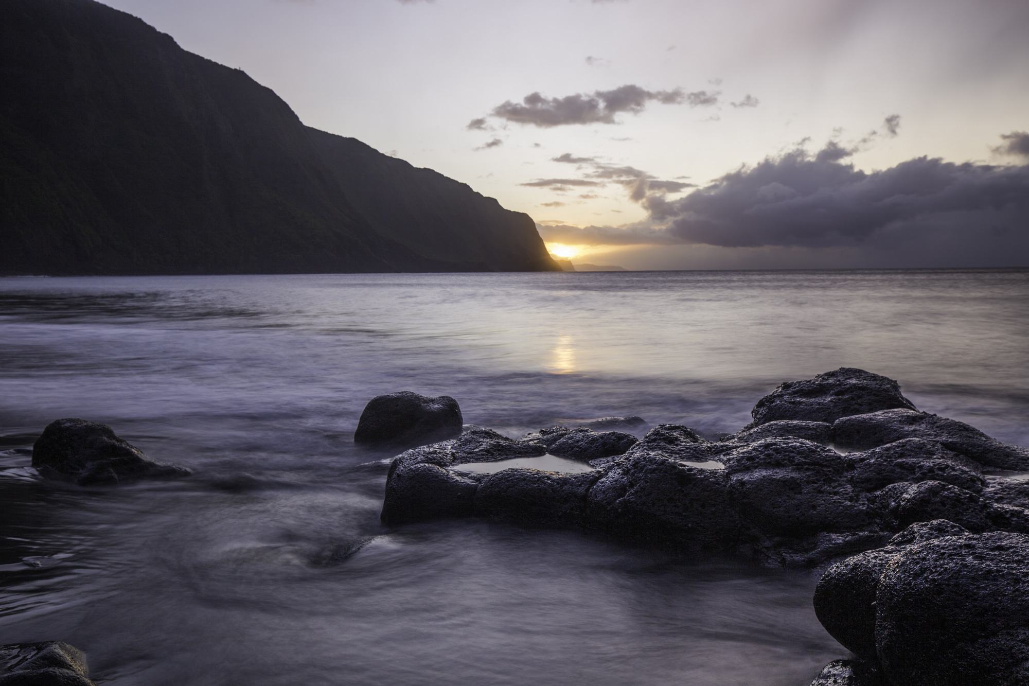 The sun setting over the ocean near pali. 