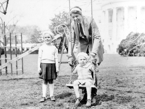 Photo of a woman with two young children at a playground.