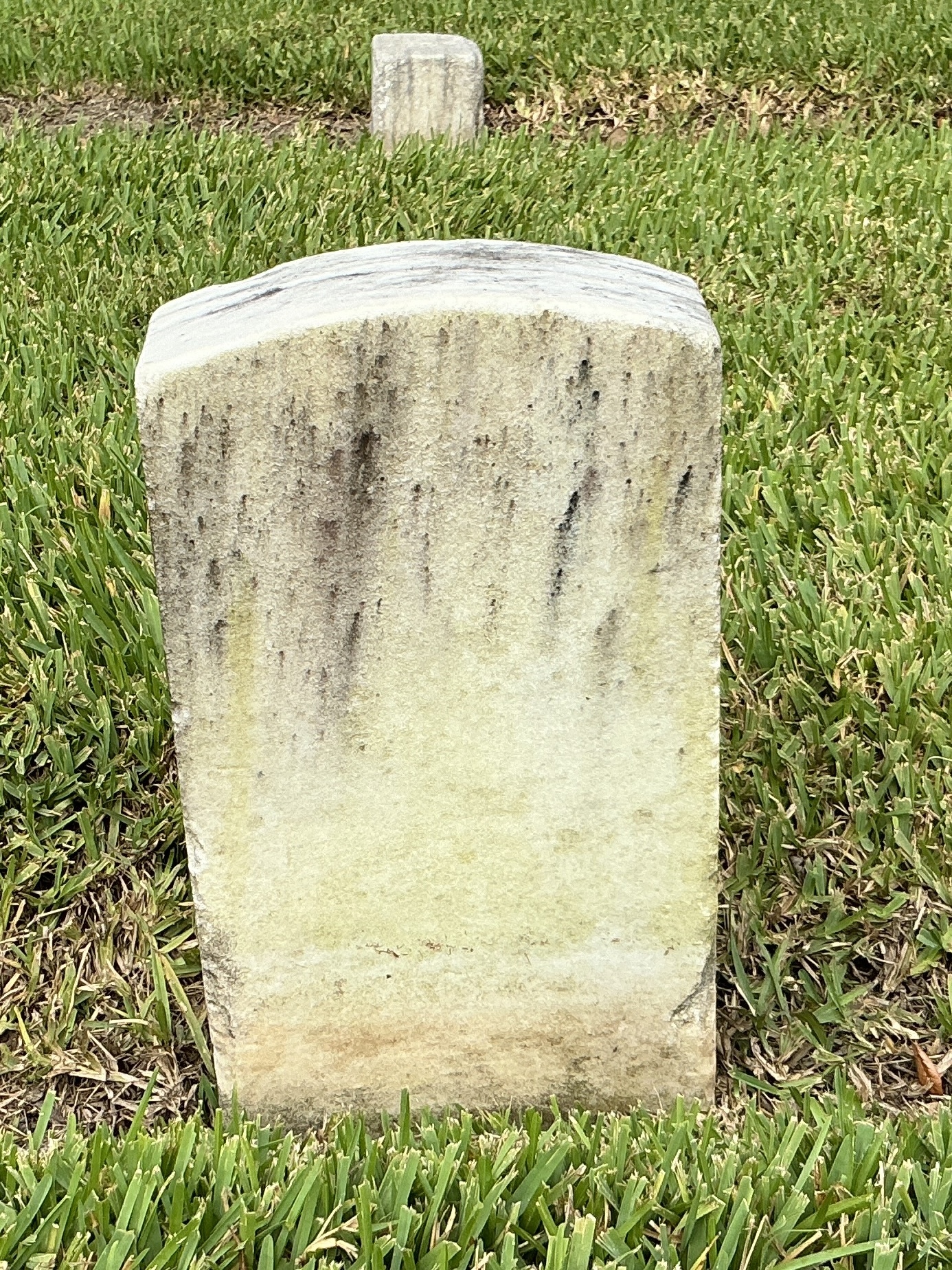 Back of historic upright marble headstone with recessed shield with recessed lettering face.
