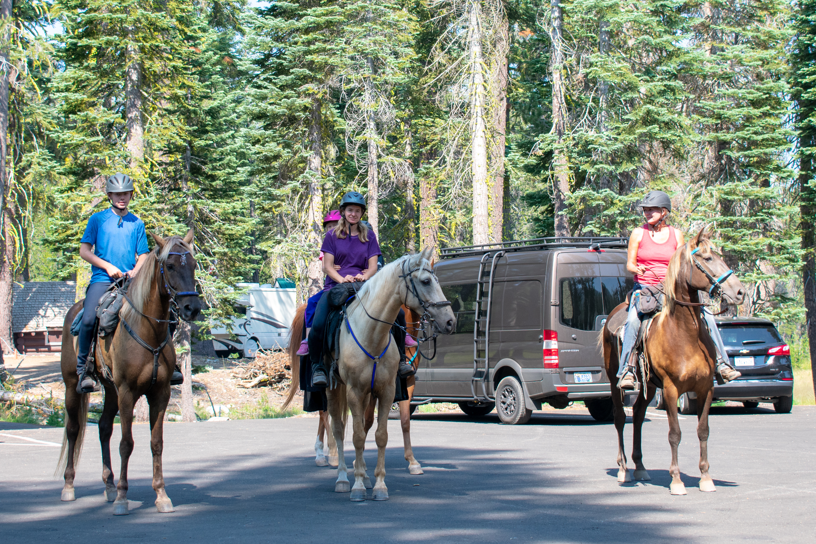 A group of four riders on three horses poses for a photo at the Summit Lake Trailhead