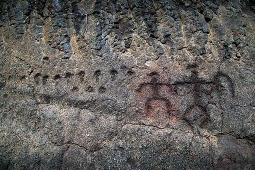 Human figure petroglyphs caved into dark gray rock